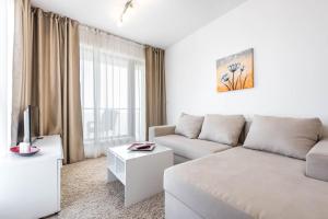 a white living room with a couch and a tv at Copacabacum Sea View in Varna City