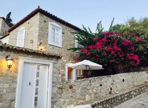 a stone house with a white door and pink flowers at Alex Hydra Summerhouse in Hydra