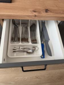 a drawer in a cabinet filled with utensils at The Urban Hero Appartment in Floreşti +17 photos