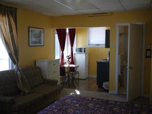 a living room with a couch and a kitchen at Motel Rive Du Lac in Saint-Zotique