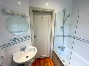 a white bathroom with a sink and a shower at Large Studio (Ground Floor) in Sutton in Cheam