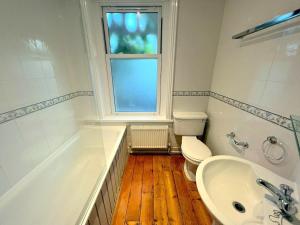a bathroom with a tub and a toilet and a sink at Large Studio (Ground Floor) in Sutton in Cheam