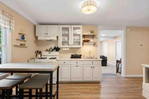 a kitchen with white cabinets and a table and chairs at Lovely Downtown Oasis Near Hospitals, Colleges, and Beaches in Amesbury +13 photos