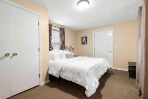 a bedroom with a large bed with white sheets at Lovely Downtown Oasis Near Hospitals, Colleges, and Beaches in Amesbury