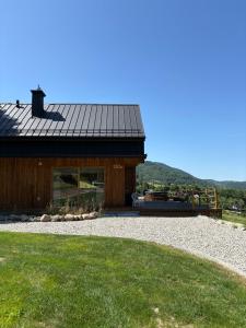 a house with a black roof and a gravel yard at Jodełkowa Stodoła in Tylmanowa