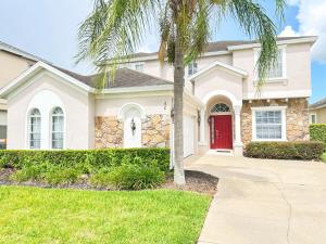 a house with a red door and a palm tree at 5 bedrooms pool home Calabay in Davenport