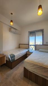 a bedroom with two beds and a window with a view at Boho Breez Mountain View Chalet in Ras Elhekma
