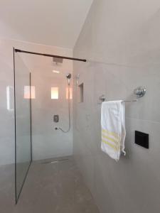 een witte badkamer met een douche en een handdoek bij Estrella Apartment Mostar in Mostar +6 foto's