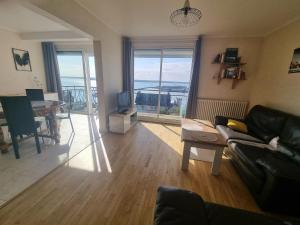 a living room with a couch and a table and a television at House for 4 people with a breathtaking view in Plérin