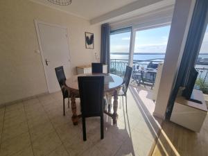 a dining room with a table and chairs and a balcony at House for 4 people with a breathtaking view in Plérin
