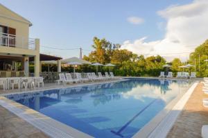 una grande piscina con sedie bianche e ombrelloni di Oliveland Apartments a Kávos