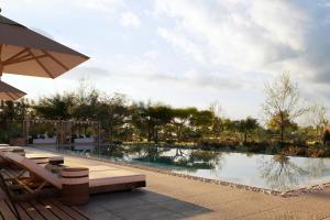 a swimming pool with benches and an umbrella next to it at Mapito Safari Camp, Serengeti, Autograph Collection in Serengeti