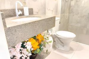 bagno con lavandino, servizi igienici e fiori di ASA | Apto Central | 250m do Alles Park | Pomerode a Pomerode Altre 15 foto