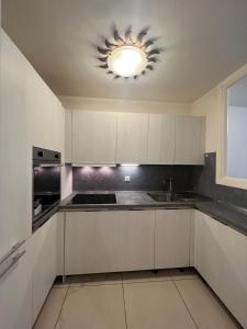 een keuken met witte kasten en een lamp bij Bilocale Le Furama in Antibes