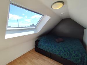 ein Schlafzimmer mit einem Bett und einem großen Fenster in der Unterkunft El pisito Quimperois duplex 2 chambres coeur de ville in Quimper