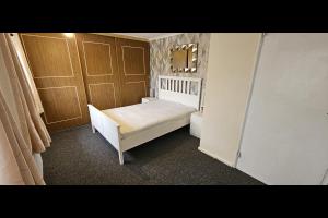 ein kleines Schlafzimmer mit einem weißen Bett und Holztüren in der Unterkunft Beautiful Tilbury House in Tilbury