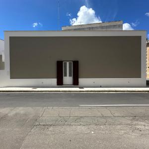 a white building with a door on the side of a street at La Dimora del Corso appartamento in Campi Salentina