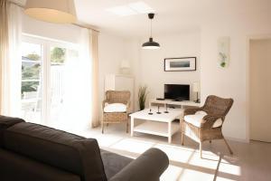 a living room with a couch and chairs and a tv at Ferienhaus Ariane - Achterwasser-Findling in Netzelkow