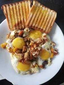 a white plate of food with eggs and toast at Village House in Blegod