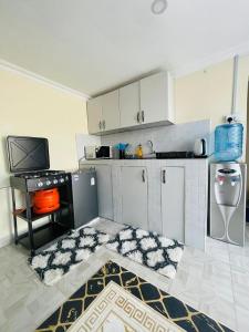a kitchen with white cabinets and a tv in it at Tausi Studio Greenspot in Ruiru