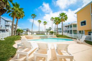 a swimming pool with white chairs and palm trees at Coconut Hut - Pet Friendly! Boardwalk to the Beach! - Pet Friendly! Boardwalk to the Beach! in Mustang Beach