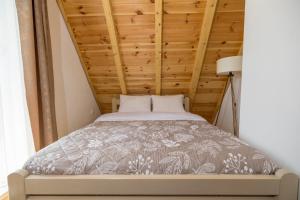 a bed in a room with a wooden ceiling at Žabljak- FamilyOasis in Žabljak