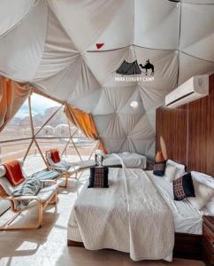 a bedroom with a tent with a bed and chairs at MIRA LUXURY CAMp in Wadi Rum +111 photos