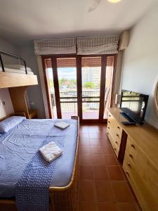a bedroom with a bed and a television and a balcony at Ampio appartamento in centro con vista - terrazze, parcheggio gratuito e Wi-Fi in Lignano Sabbiadoro
