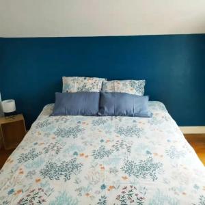a bed in a bedroom with a blue wall at La Maison d'Alinès in Figueira da Foz