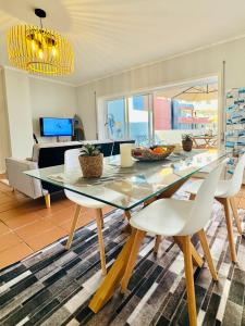 a dining room with a glass table and white chairs at Cabedelo Beach Loft in Darque +50 photos