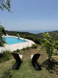 two chairs sitting in the grass near a swimming pool at Villa Ela - Cape of Rodon in Draç