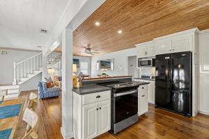 une cuisine avec des armoires blanches et un réfrigérateur noir dans l'établissement Cute Beach Cottage Steps to the Beach! Panama City Beach, FL!, à Laguna Beach