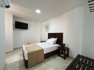 a bedroom with a bed and a tv on the wall at Santa Elena Hotel in Ocaña