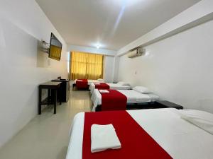una camera con quattro letti con lenzuola rosse e bianche di Hotel Luxor Pucallpa a Pucallpa Altre 18 foto