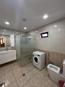 Un baño con lavadora y un inodoro. en Gabala Double villa, en Gabala