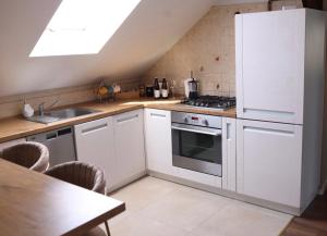 a kitchen with white cabinets and a sink and a stove at Apartament na poddaszu in Sandomierz