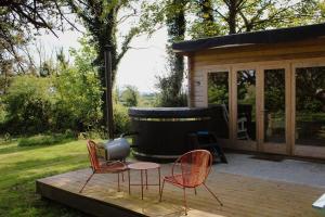 two chairs and a table on a deck in front of a hot tub at Lime cottage in Kilrush