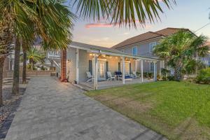 une maison avec un patio et une cour avec des palmiers dans l'établissement Cute Beach Cottage Steps to the Beach! Panama City Beach, FL!, à Laguna Beach
