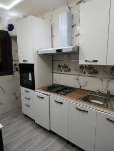 a white kitchen with a stove and a sink at La maison bleu in Oulad Akkou