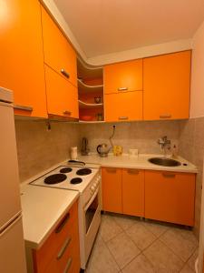 cocina con armarios de color naranja y horno con fogones en Apartman Luka5, en Petrovac na Moru