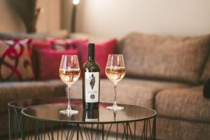 カランバカにあるMary's Modern and Elegant apartmentのワイングラス2杯付きのテーブルに座ったワイン1本