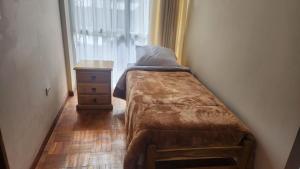 a small bed in a room with a dresser and a window at Departamento entero soleado in Sucre