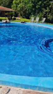 a large blue swimming pool with chairs in it at Cabañas la Granja Rincón de Guayabitos in Rincon de Guayabitos
