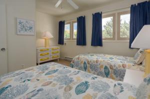 zwei Betten in einem Schlafzimmer mit blauen Vorhängen in der Unterkunft Mariners court 204 in Rehoboth Beach