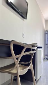 a chair in a room with a tv on the wall at Hotel Villa Rica in Cassilândia +4 photos