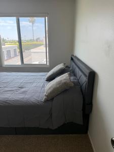 ein Bett mit Kissen darauf in einem Zimmer mit Fenster in der Unterkunft Two Bedroom Condo in Huntington Beach in Huntington Beach + 18 Fotos