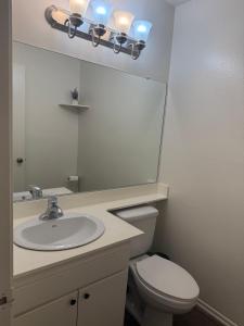 ein Badezimmer mit Waschbecken, Toilette und Spiegel in der Unterkunft Two Bedroom Condo in Huntington Beach in Huntington Beach