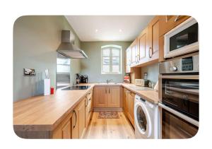 a kitchen with wooden cabinets and a washer and dryer at The Hurst Stable in Wheaton Aston