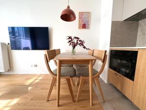 a kitchen with a wooden table and chairs at Len Apartments One Gdańsk Sobieszewo Baltic Line blisko morza na Wyspie Sobieszewskiej dla rodzin przyjazny zwierzętom z tarasem in Gdańsk