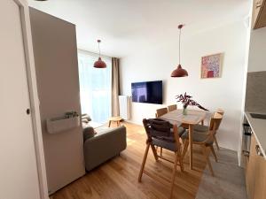 a kitchen and living room with a table and chairs at Len Apartments One Gdańsk Sobieszewo Baltic Line blisko morza na Wyspie Sobieszewskiej dla rodzin przyjazny zwierzętom z tarasem in Gdańsk